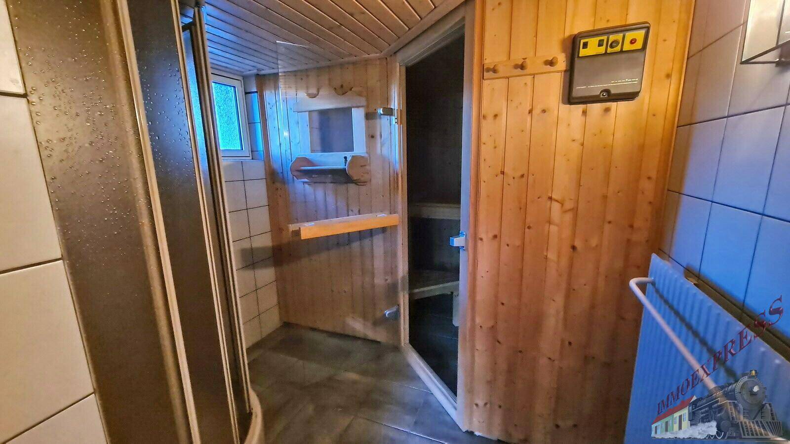 Eingang zu einer Holzsauna mit angrenzendem Duschbereich und Fliesenboden.