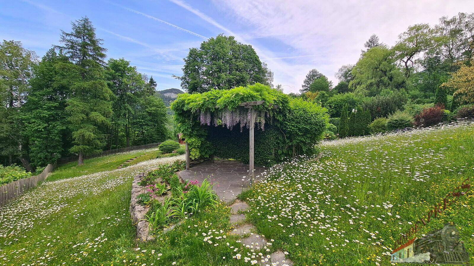Eine mit Pflanzen bewachsene Pergola bietet einen schattigen Sitzbereich im weitläufigen Garten.