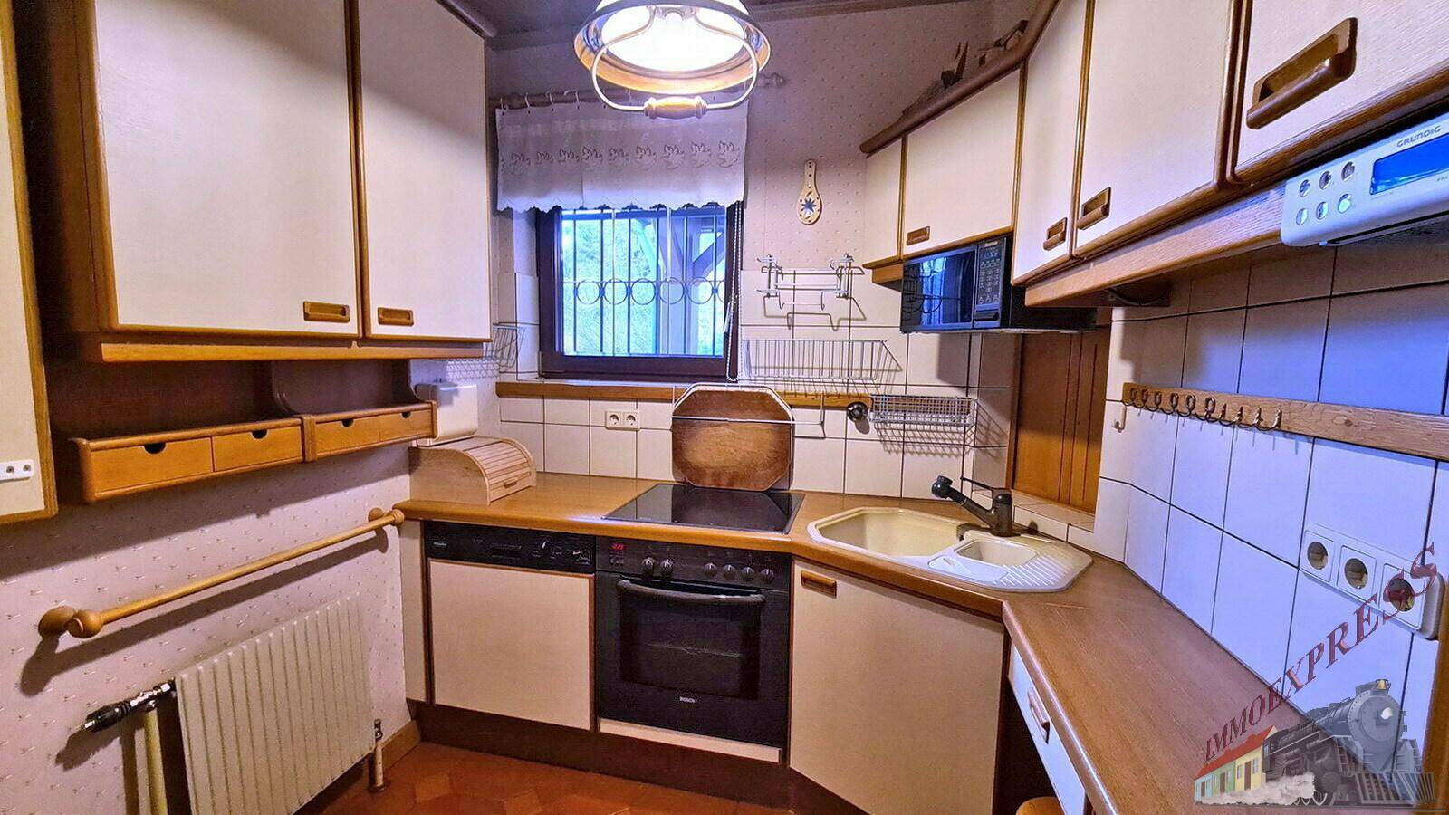 Funktionale Küche mit Einbauschränken, Herd und Spüle, im traditionellen Stil gehalten.