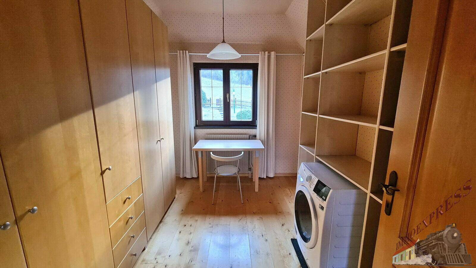 Praktischer Hauswirtschaftsraum mit Waschmaschine, Regalen und einem kleinen Arbeitsbereich.