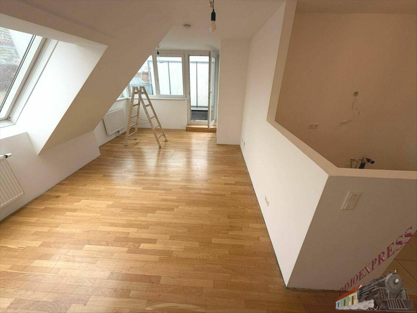 Geräumiges Dachgeschosszimmer mit Holzboden und Zugang zu einem kleinen Außenbereich.