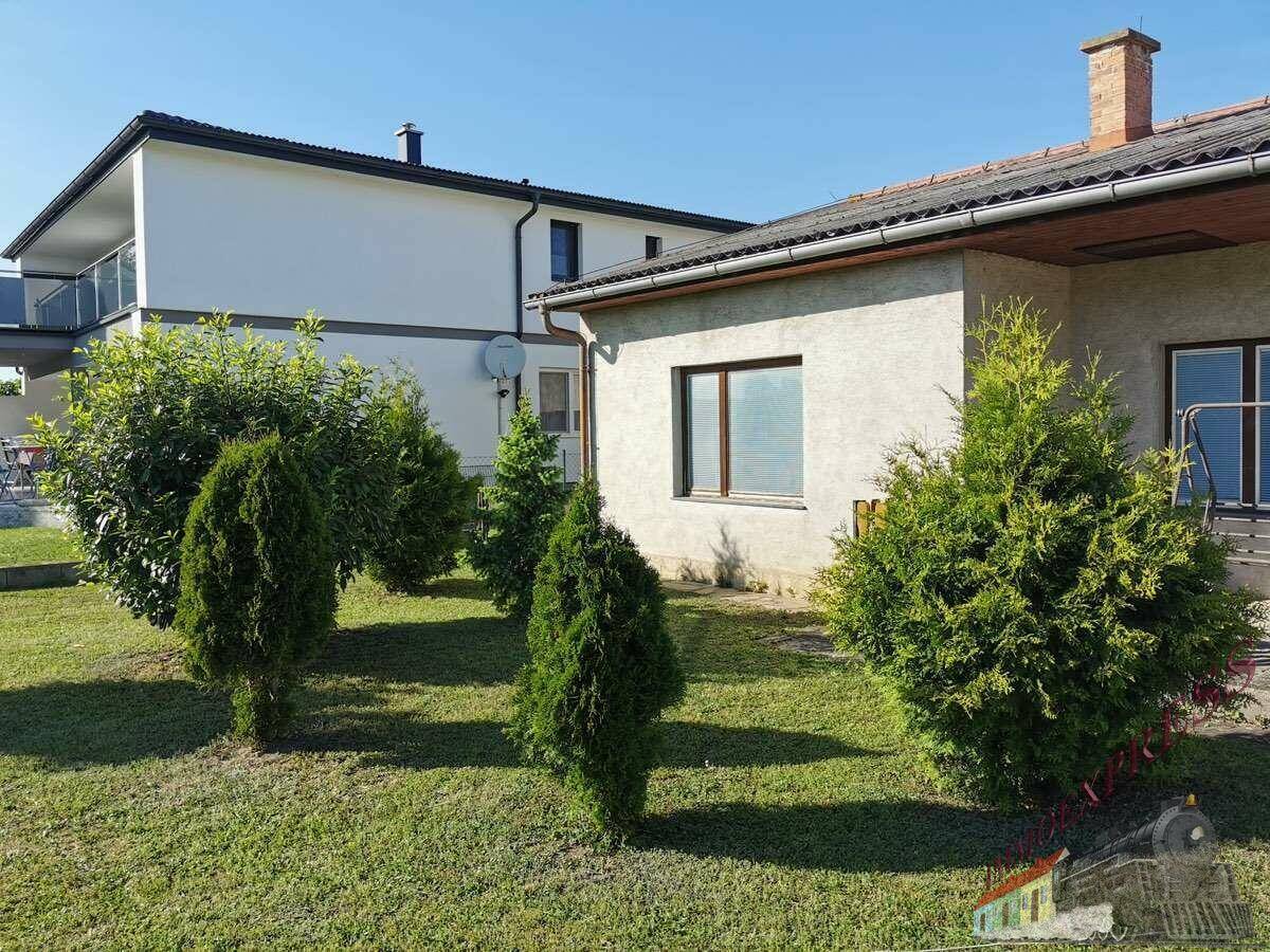 Seitenansicht des Hauses mit Garten und Blick auf das benachbarte moderne Gebäude.