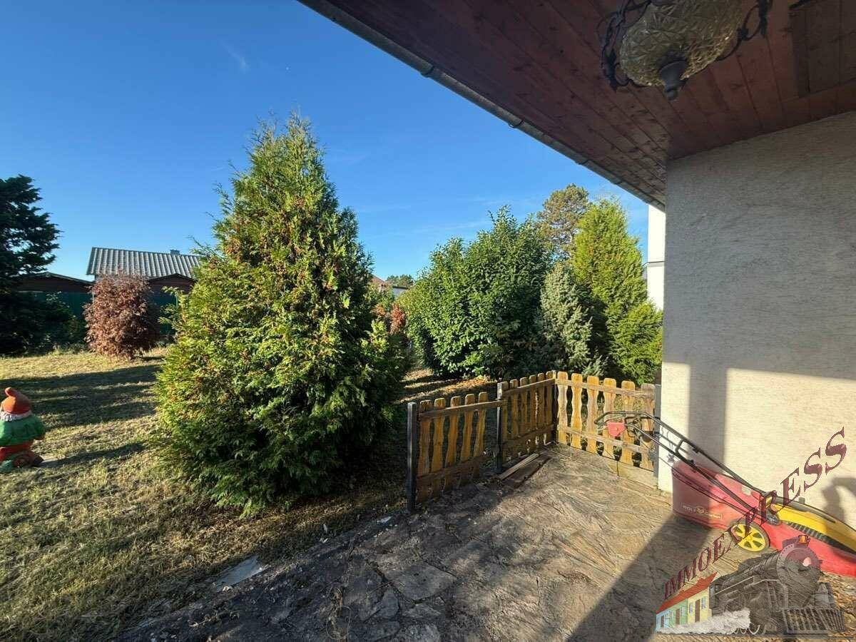 Überdachter Terrassenbereich mit Blick in den grünen Garten und auf die umliegende Landschaft.