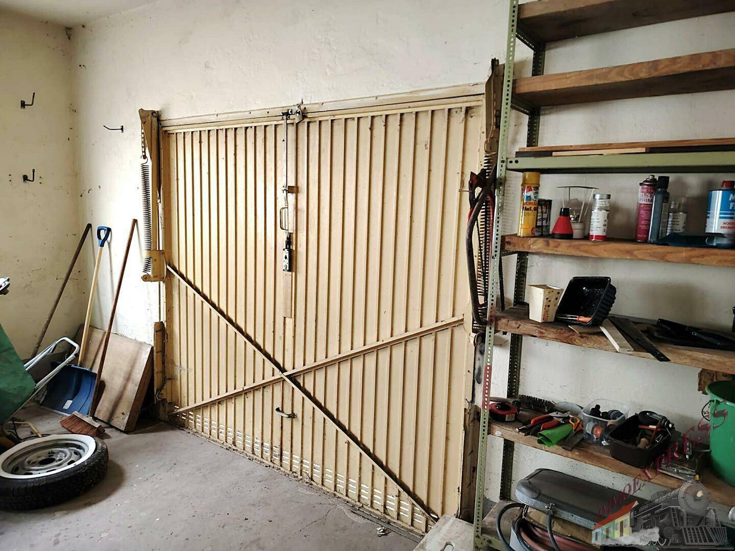 Geräumige Garage mit einem großen Tor, Regalen und verschiedenen Werkzeugen.