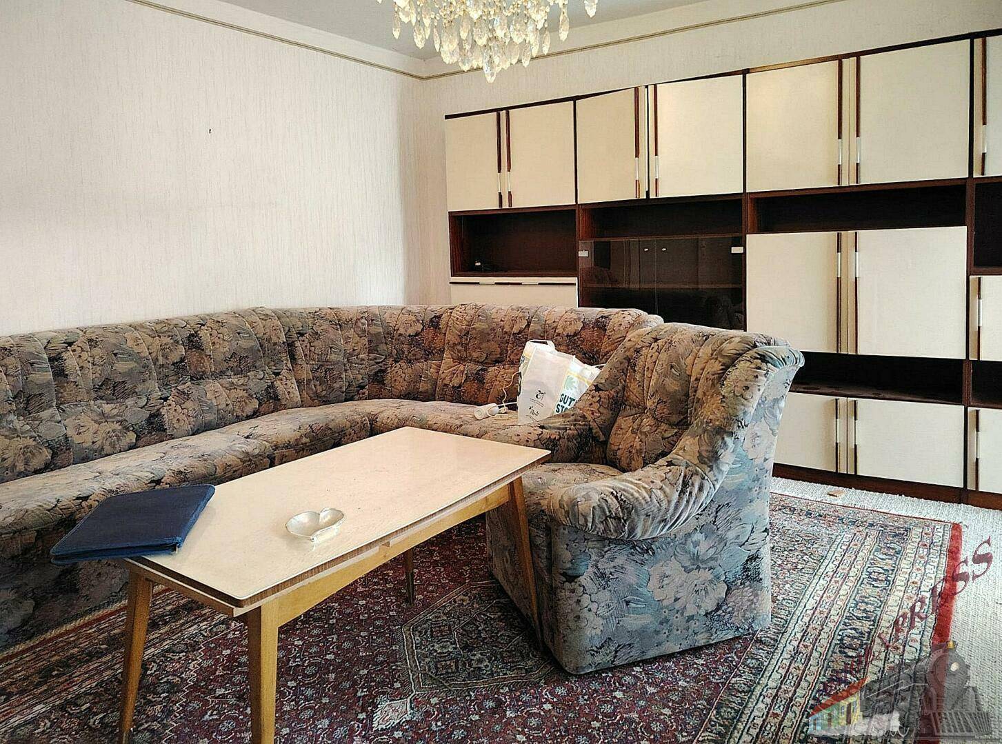 Gemütliches Wohnzimmer mit großem Ecksofa, Teppich und einer Schrankwand im Vintage-Stil.