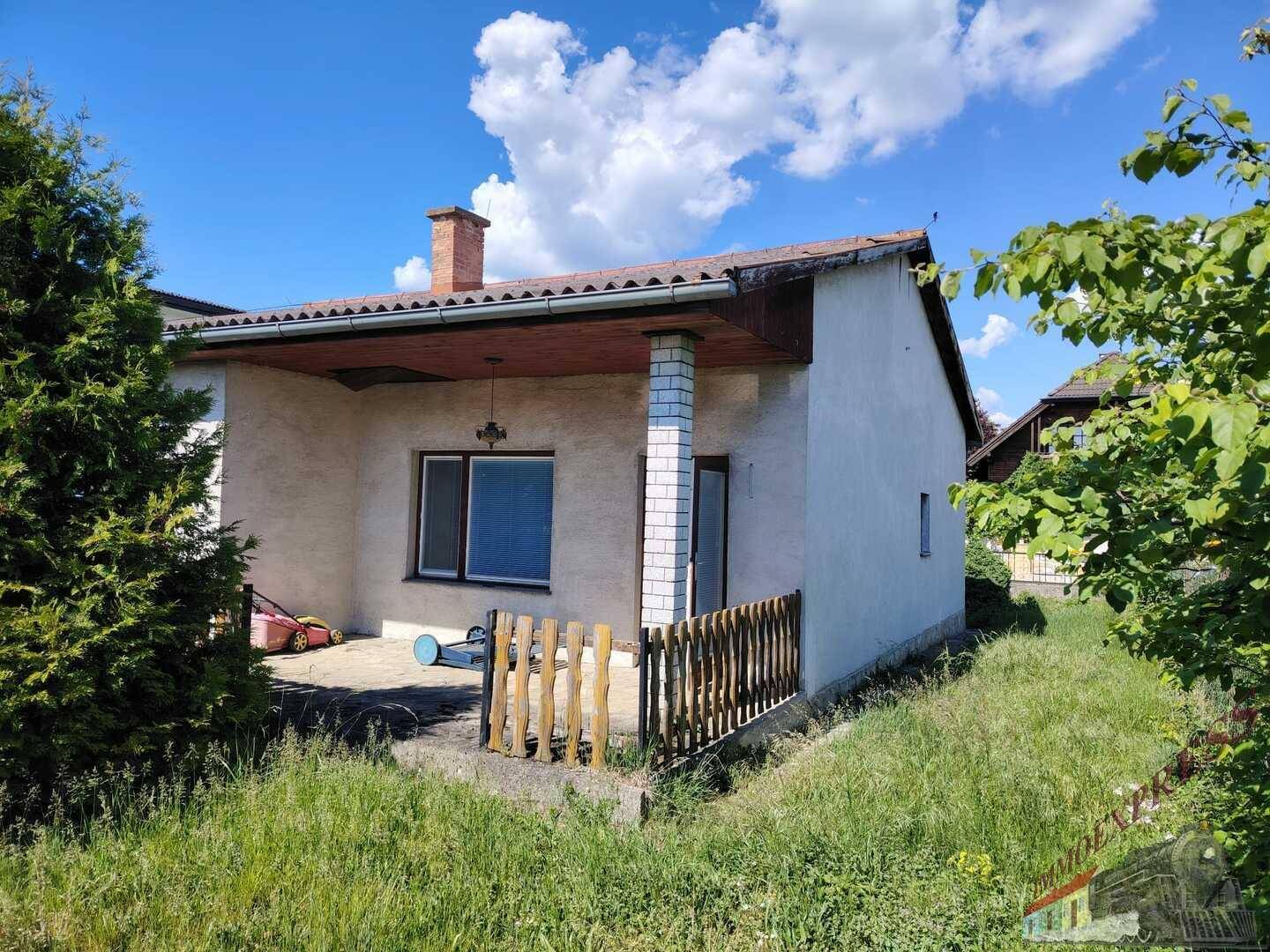 Seitliche Ansicht des Hauses mit einer kleinen überdachten Terrasse und angrenzendem Gartenbereich.