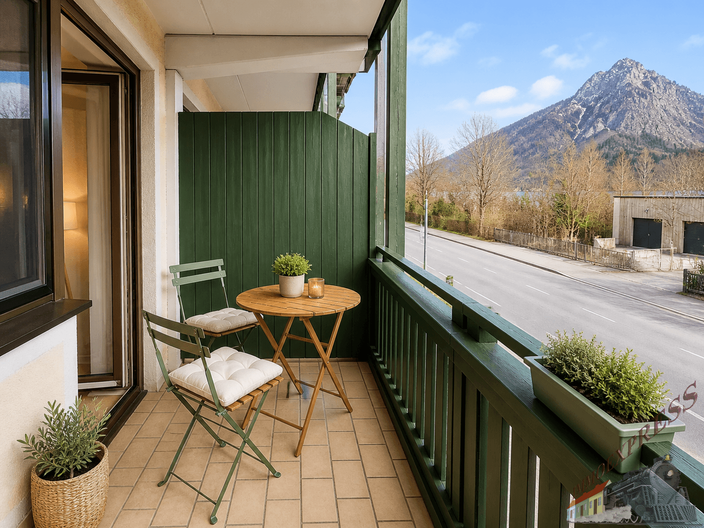 Balkon mit Sitzgelegenheiten und weitem Blick auf die Berge und die darunterliegende Straße.