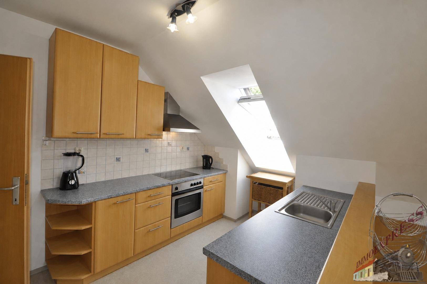 Helle Küche mit Holzschränken, modernen Geräten und einem Dachfenster für natürliches Licht.
