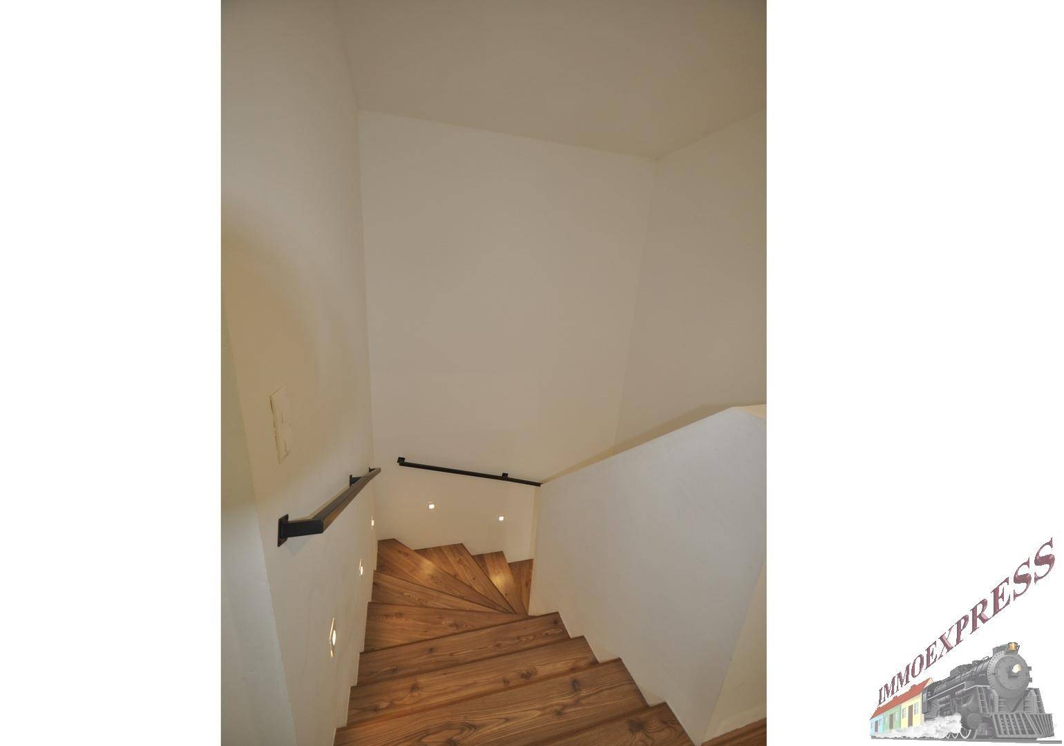 Moderne Holztreppe mit schlichtem Geländer und indirekter Beleuchtung.
