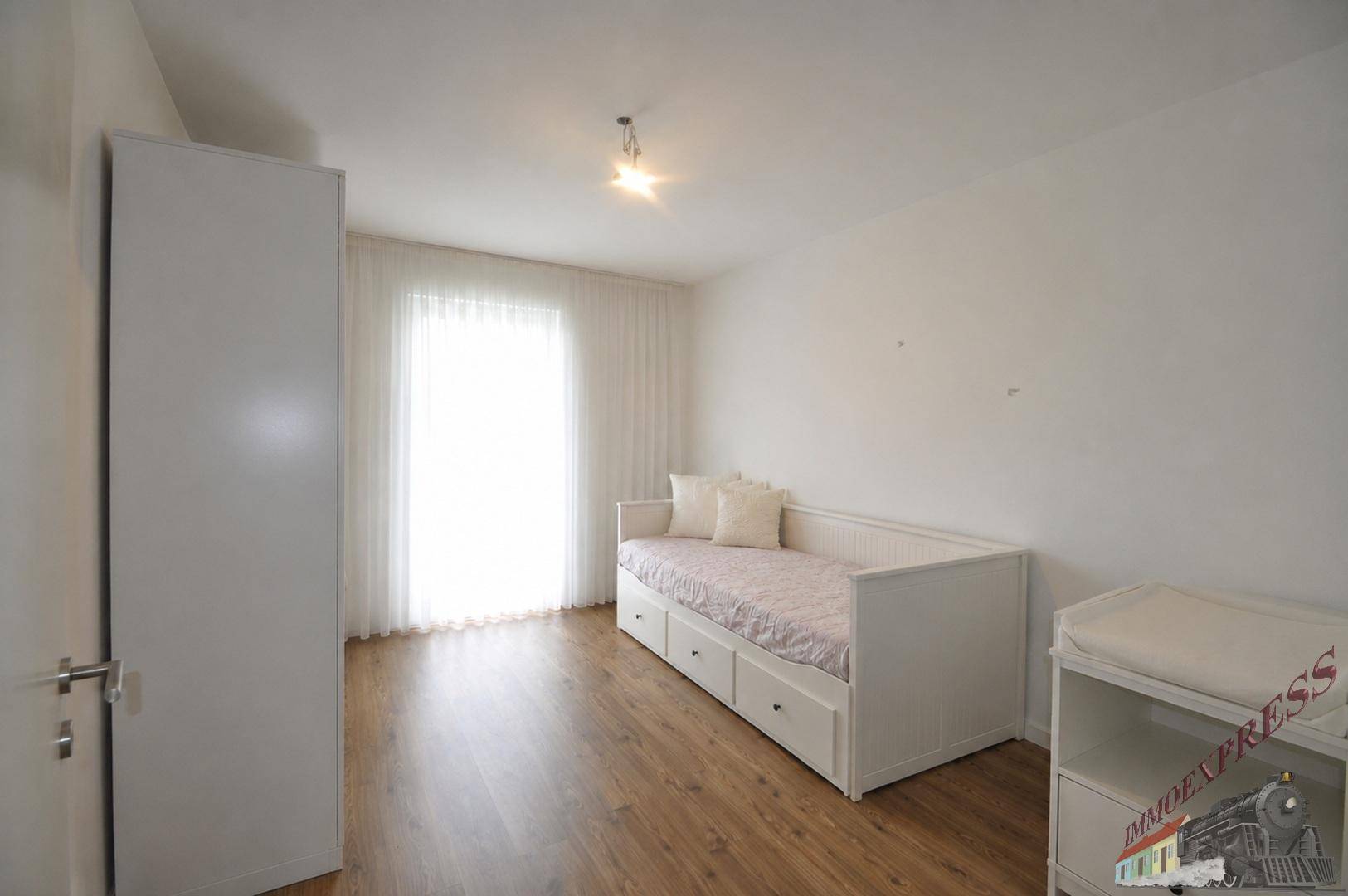Helles Kinder- oder Gästezimmer mit Tagesbett und Zugang zum Balkon.