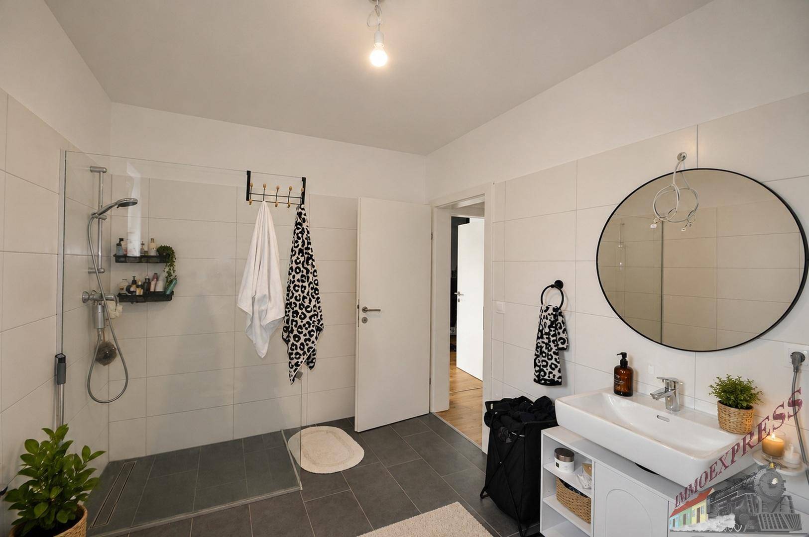 Modernes Badezimmer mit großer begehbarer Dusche, Einzelwaschbecken und Fliesenboden.