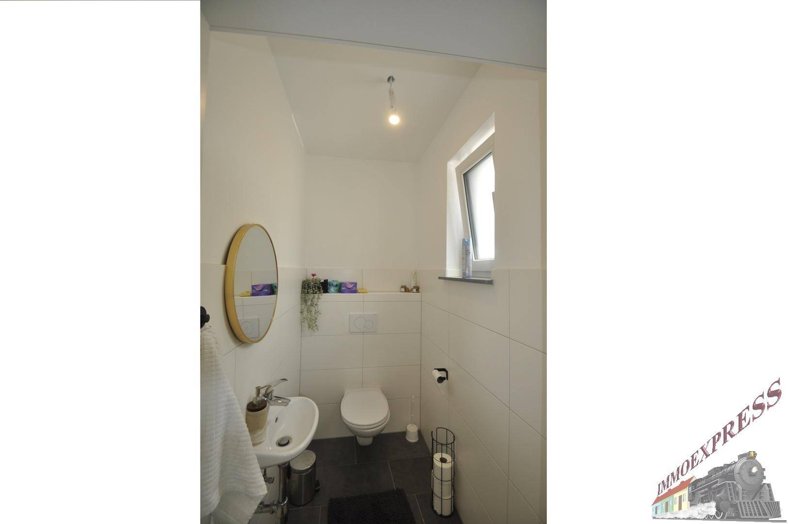 Modernes Gäste-WC mit Waschbecken, Toilette und Fenster für Tageslicht.