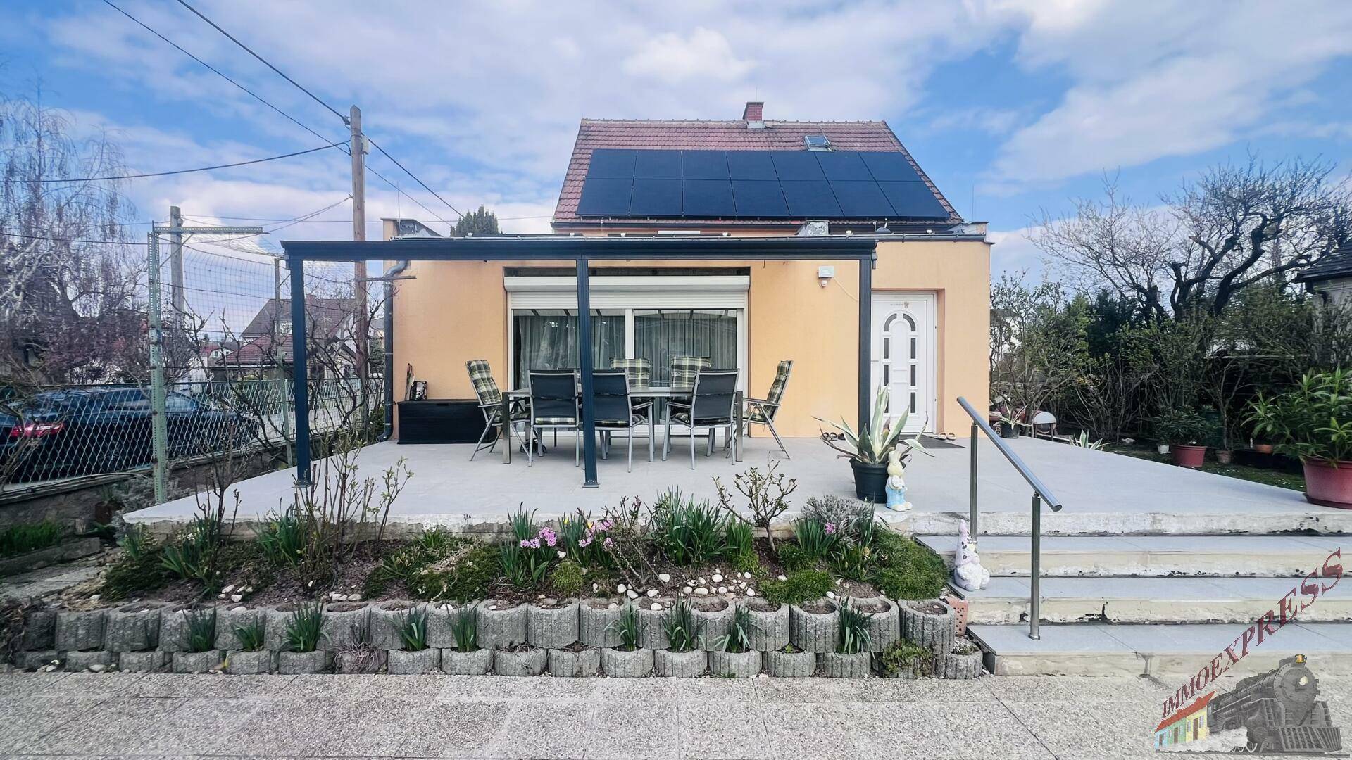 Überdachte Terrasse mit Gartenmöbeln und Photovoltaikanlage auf dem Dach des Hauses.