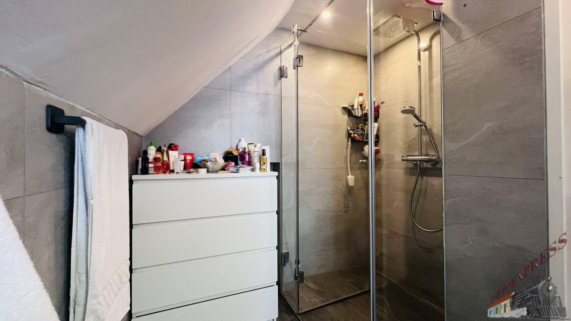 Modernes Badezimmer mit Duschkabine, grauen Fliesen und Dachschräge.
