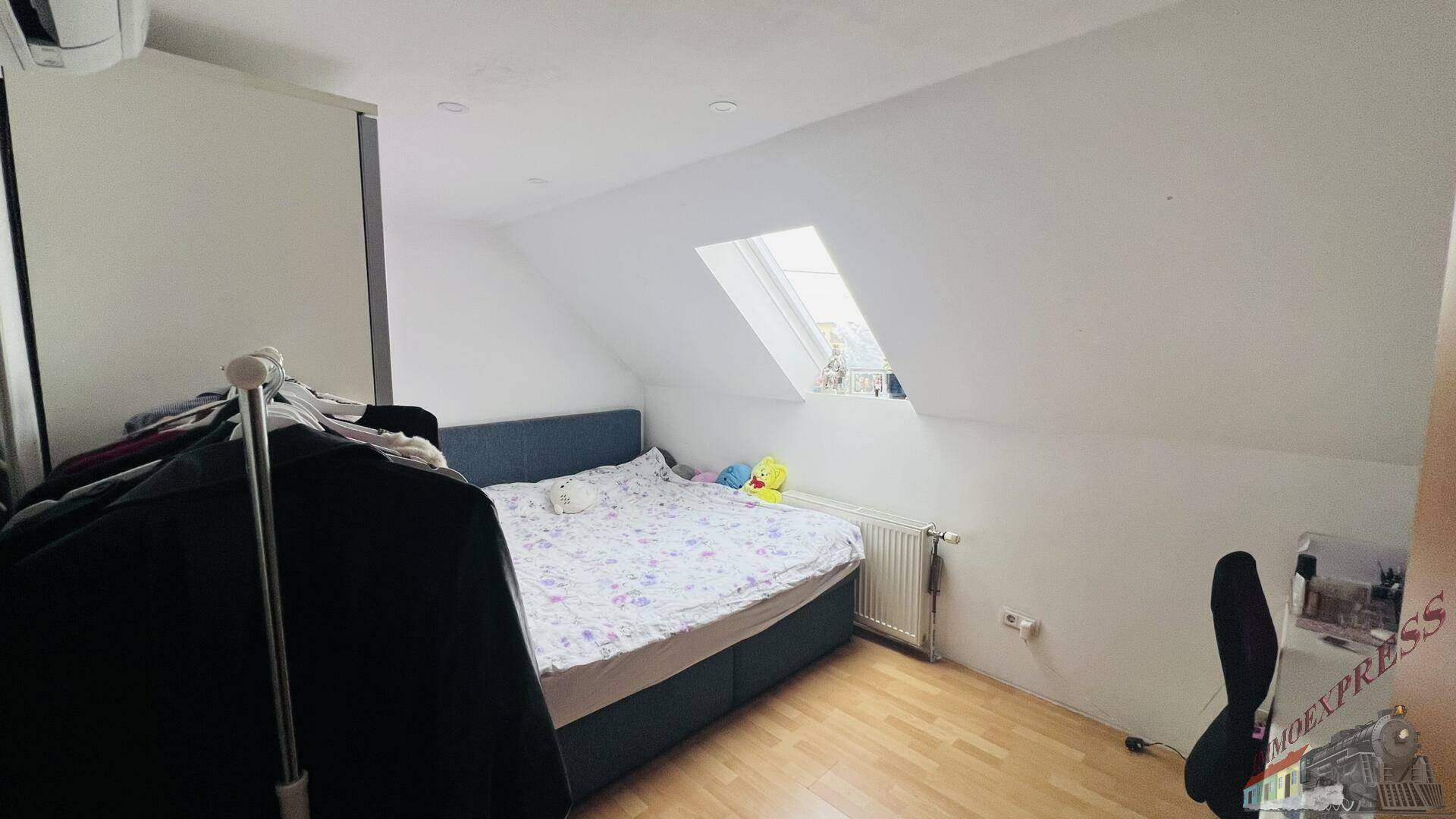 Schlafzimmer im Dachgeschoss mit Dachfenster, Doppelbett und Holzboden.