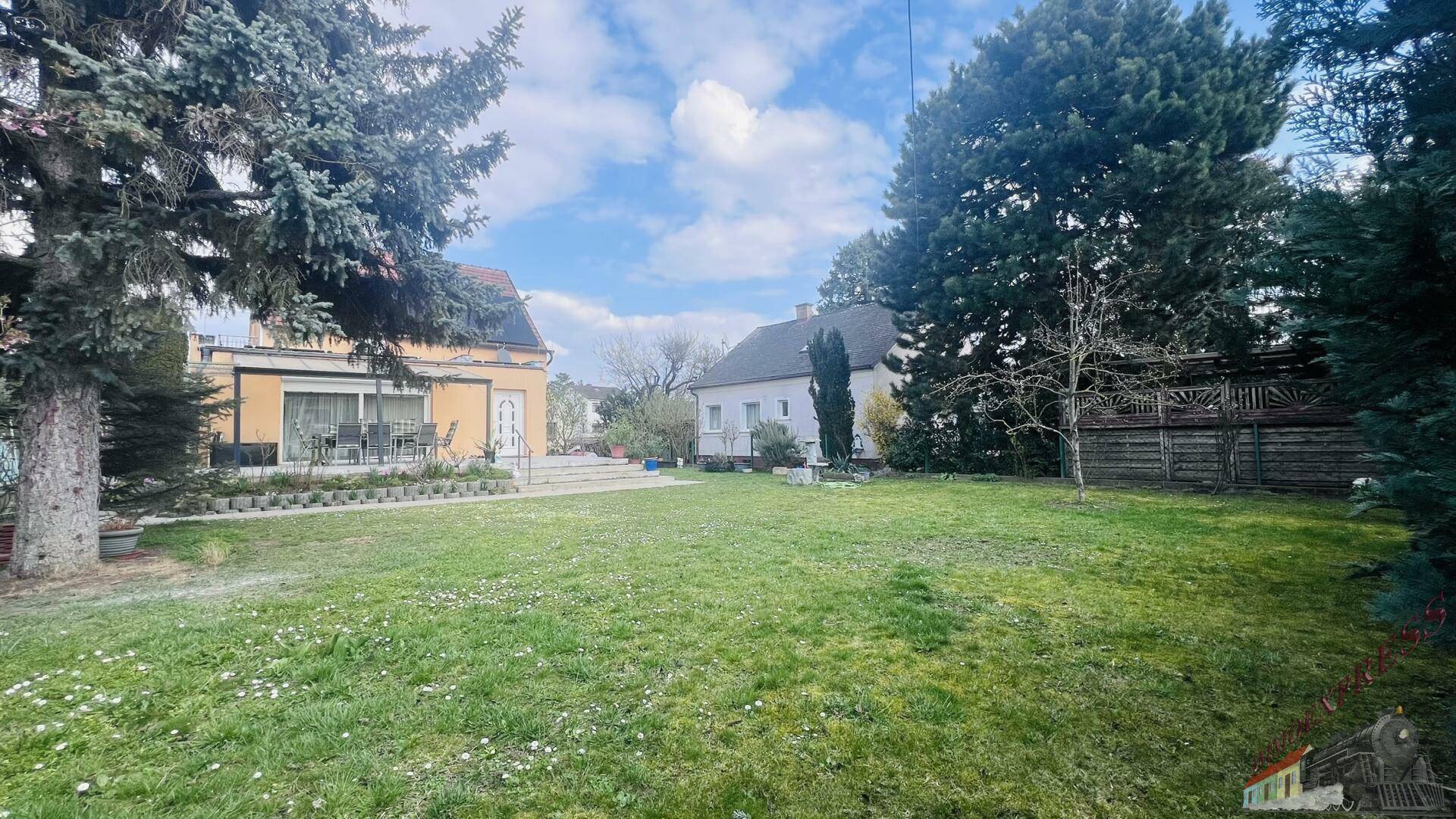 Weitläufiger Garten mit großer Rasenfläche und Blick auf das Wohnhaus im Hintergrund.