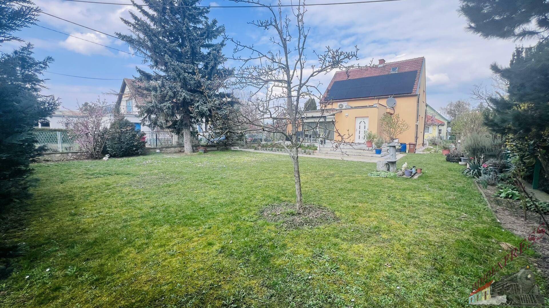 Weitläufiger Garten mit Rasenfläche und Blick auf das Haus mit Photovoltaikanlage.