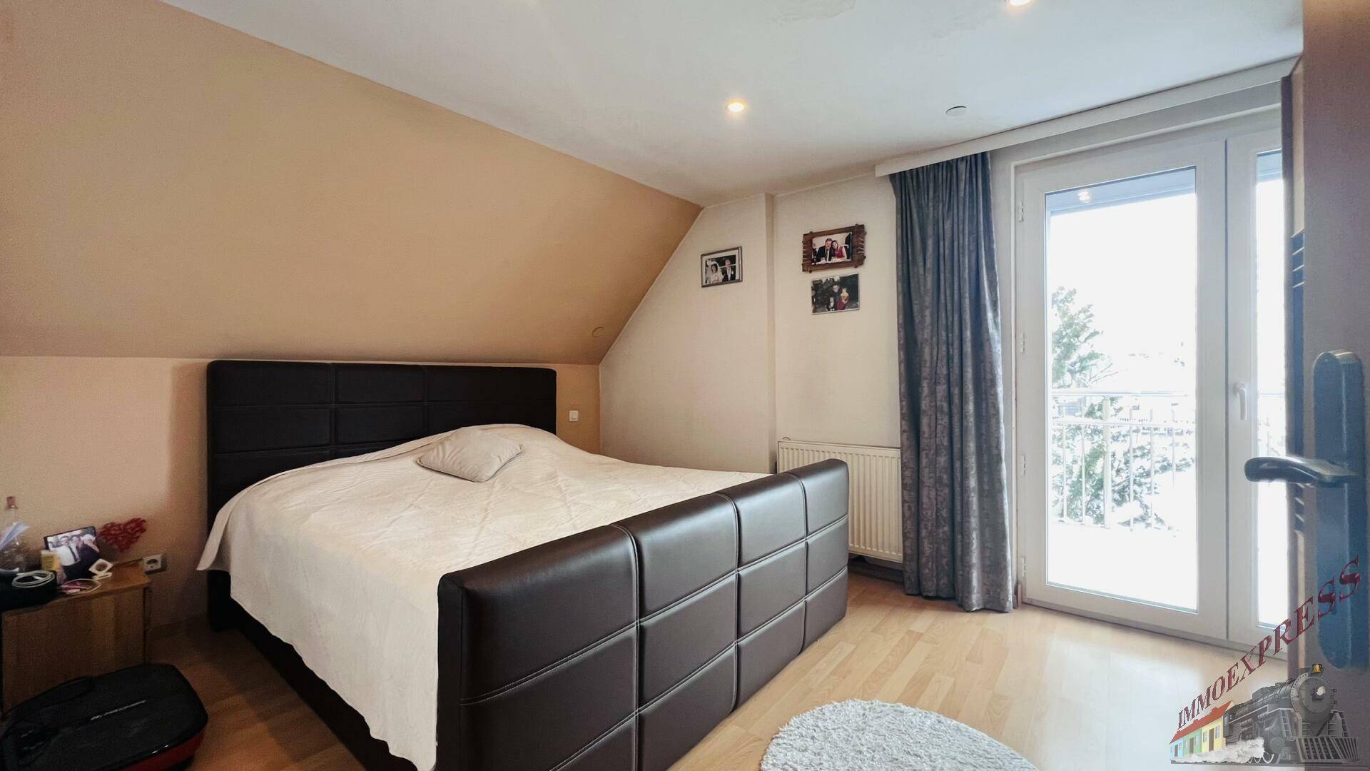 Schlafzimmer mit Doppelbett, Holzboden und Zugang zu einem französischen Balkon.