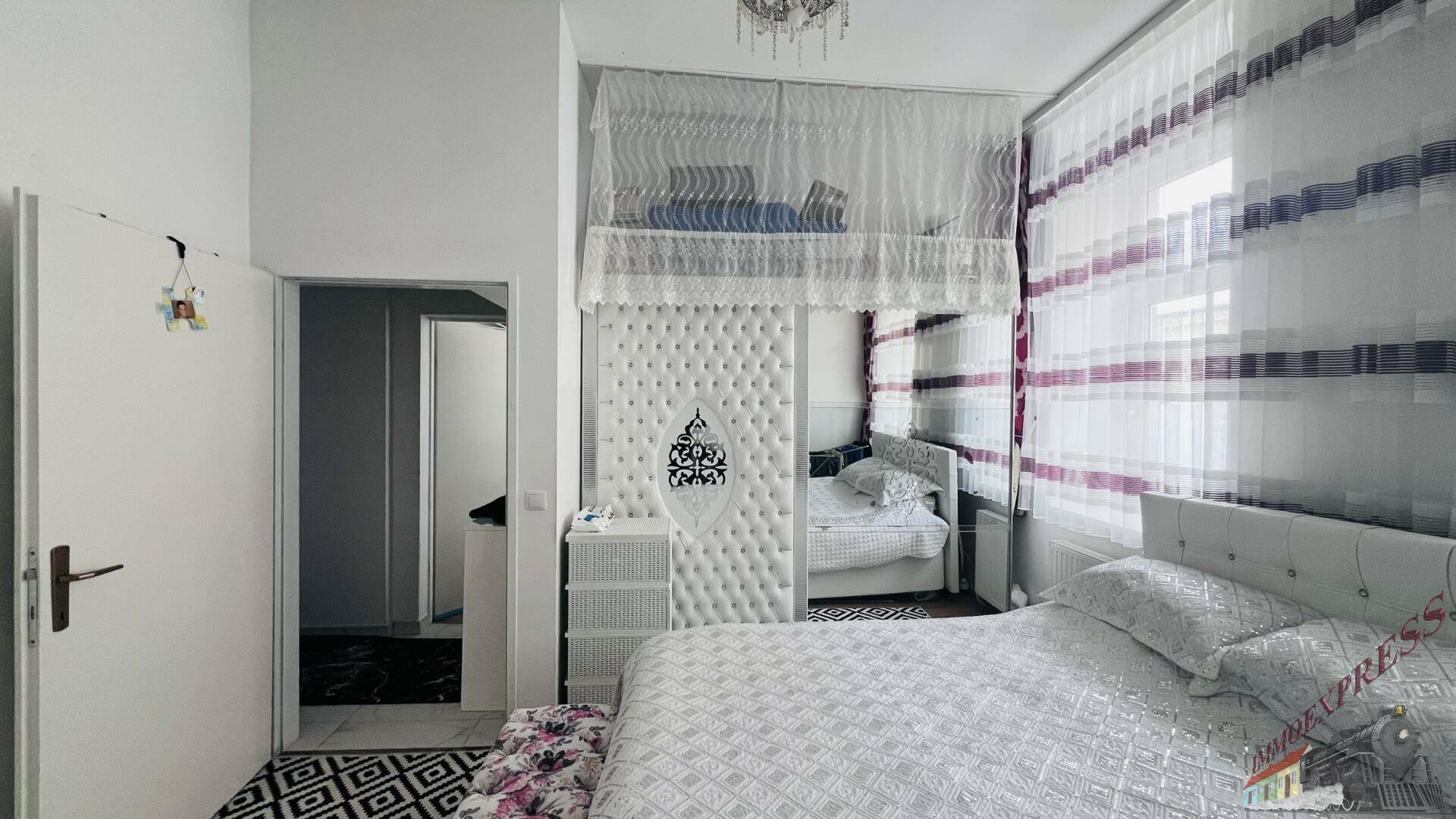 Schlafzimmer mit Doppelbett, einem Hochbett und einem Spiegelschrank, hell und funktional eingerichtet.