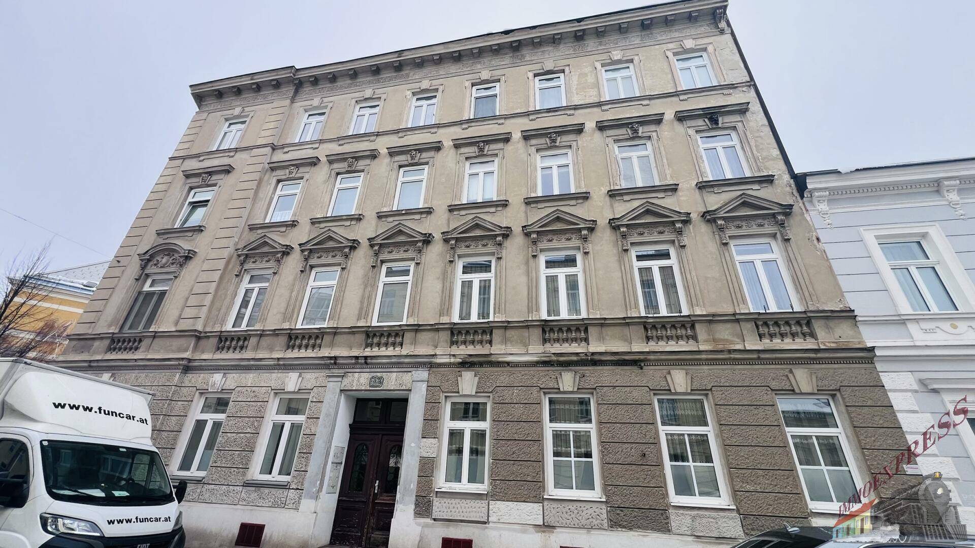 Historische Fassade eines Mehrfamilienhauses mit vielen Fenstern und klassischer Architektur.