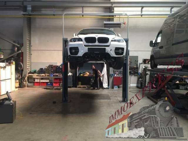 Kfz-Werkstatt mit Hebebühne und einem weißen SUV, bereit für Reparaturen und Wartungsarbeiten.