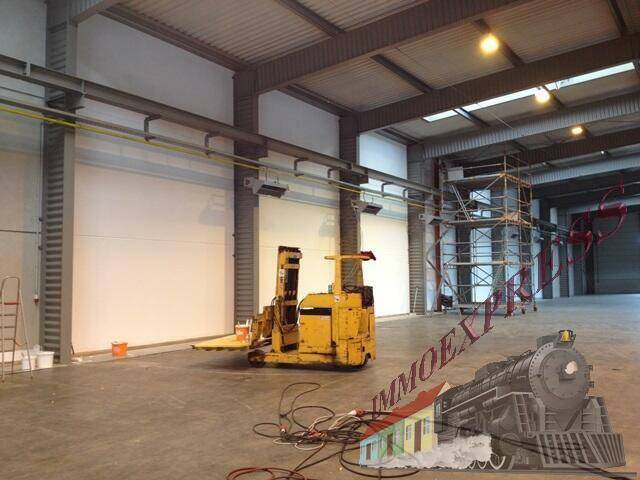 Leere Werkstatthalle mit hohen Decken, Kranbahn und einem Gabelstapler auf dem Betonboden, bereit für Nutzung.