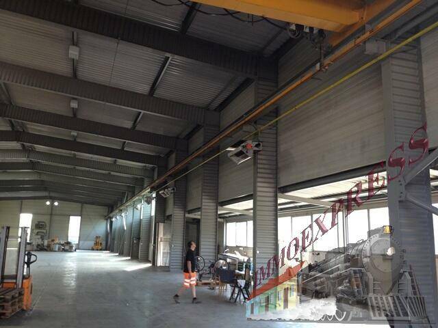 Große Werkstatthalle mit hohen Decken, Kranbahn und viel Tageslicht durch die Fenster, ideal für Produktion.