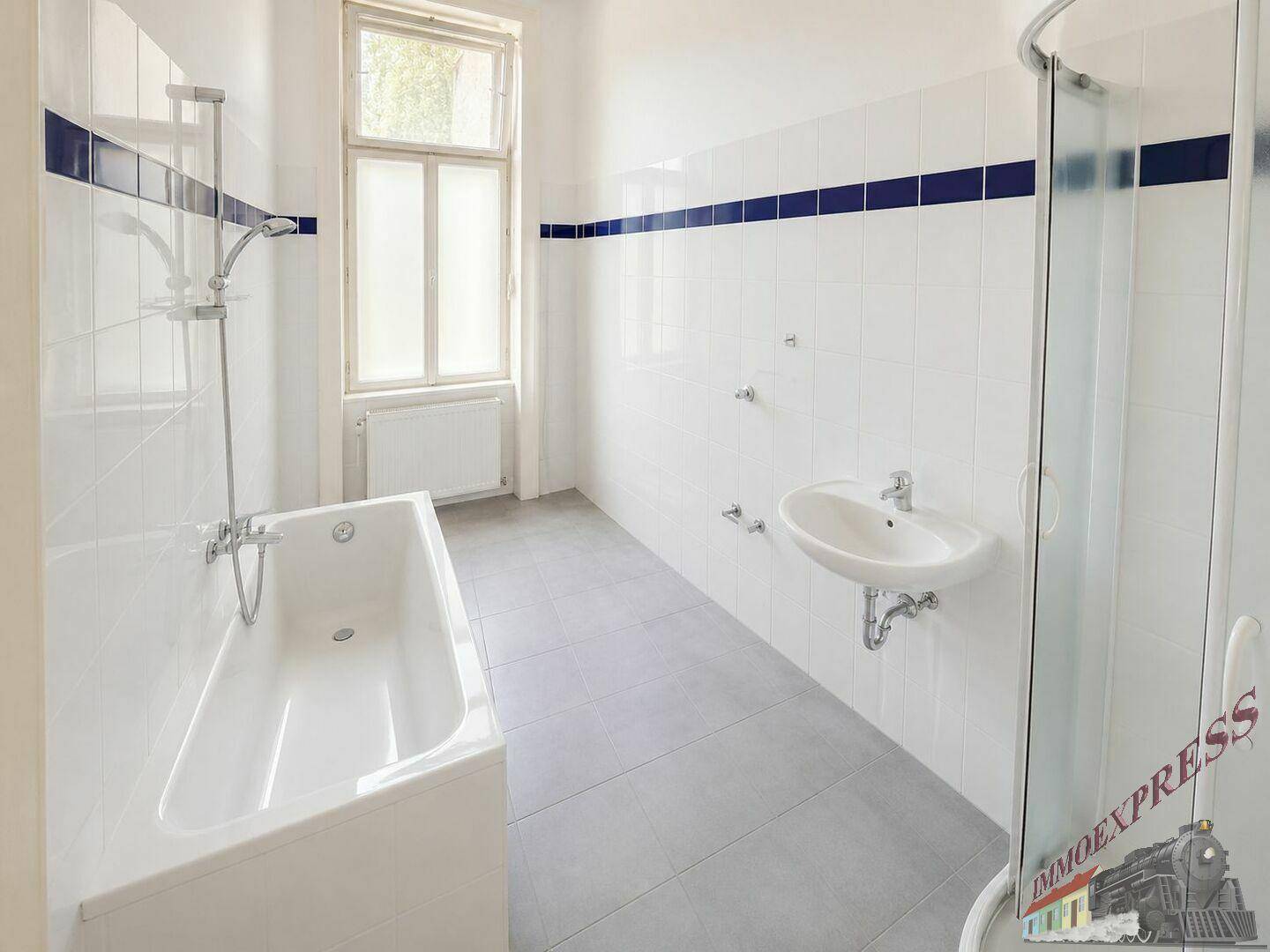 Helles Badezimmer mit Badewanne, Duschkabine, Waschbecken, Fenster und blauen Akzentfliesen.