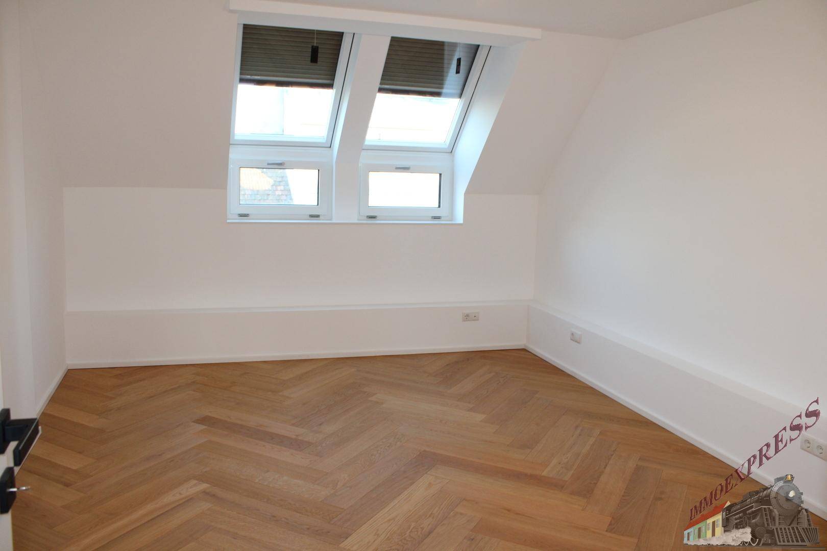 Gemütliches Schlafzimmer im Dachgeschoss mit zwei Dachfenstern und Fischgrätparkett.