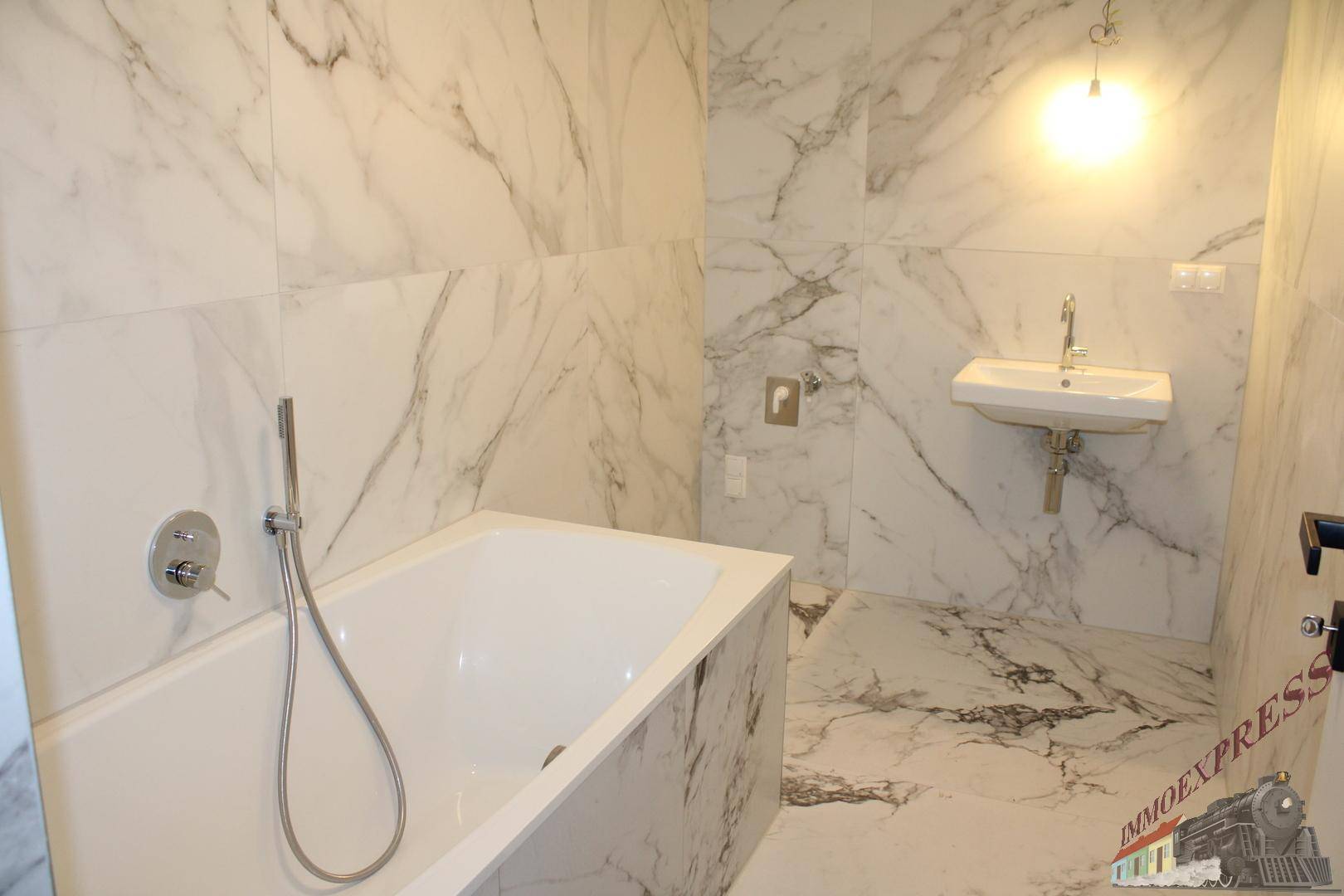 Geräumiges Badezimmer mit Badewanne, Marmorfliesen und modernem Waschbecken.
