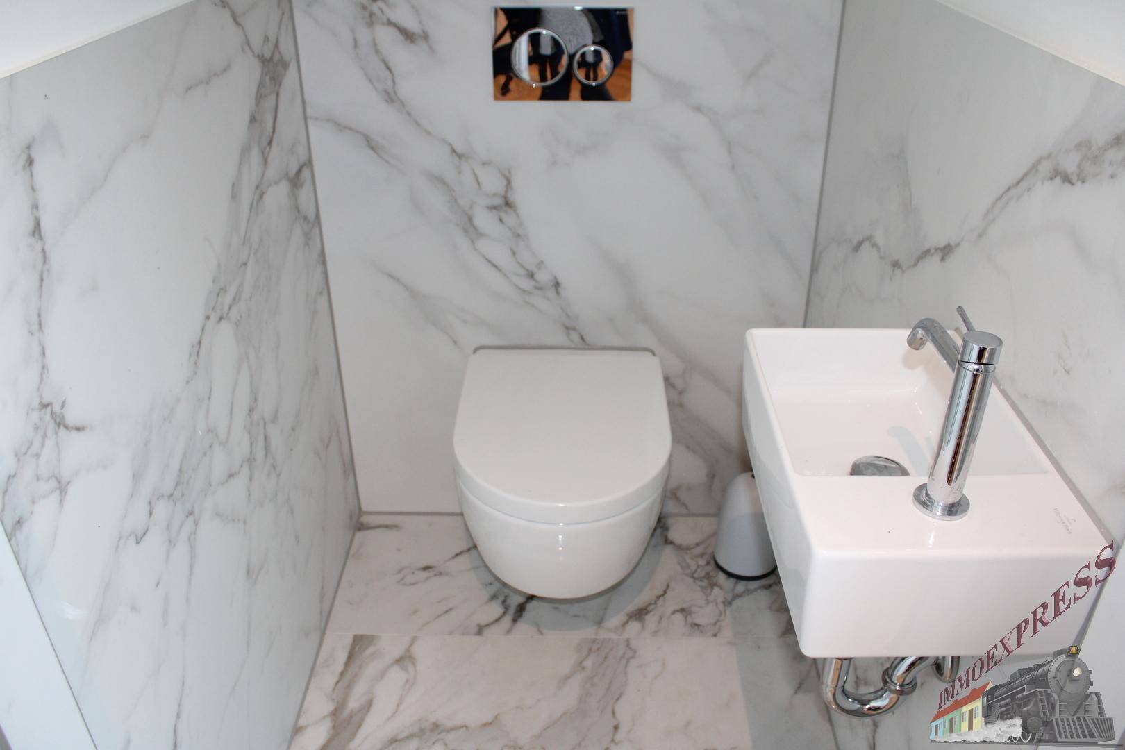 Stilvolles Gäste-WC mit Marmorfliesen, wandhängendem WC und kleinem Design-Waschbecken.