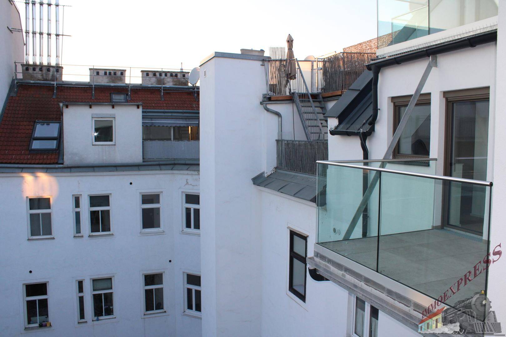 Außenansicht eines modernen Balkons mit Glasgeländer und Blick auf die umliegenden Gebäude.