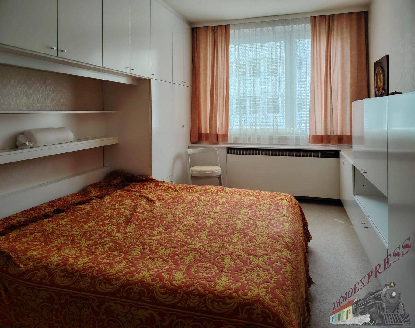 Schlafzimmer mit großem Bett, Einbauschränken und Fenster für natürliches Licht.