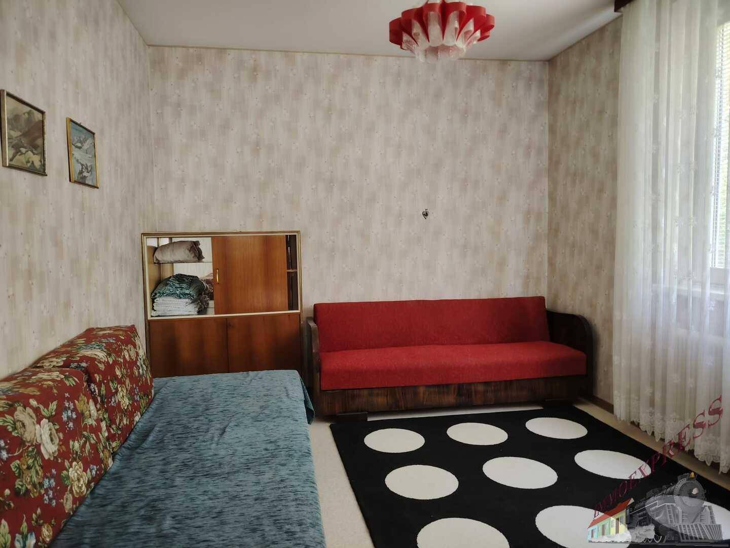 Gemütlicher Raum mit zwei Sofas, Teppich und Tapeten, ideal als Gäste- oder Wohnzimmer.