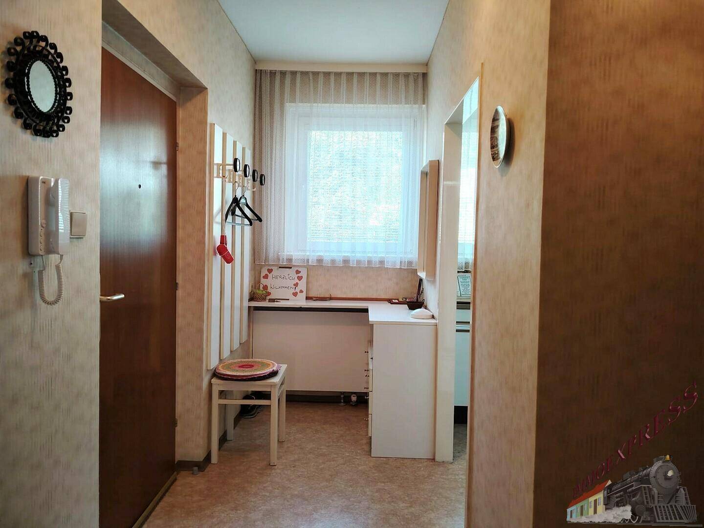 Heller Flur mit Garderobe, Spiegel und kleinem Schreibtisch, einladender Eingangsbereich.