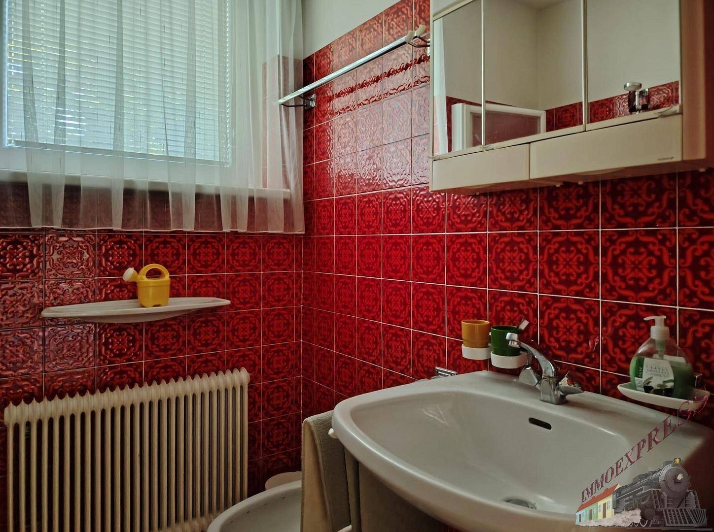 Badezimmer mit roten Fliesen, Waschbecken, Bidet und Spiegelschrank.