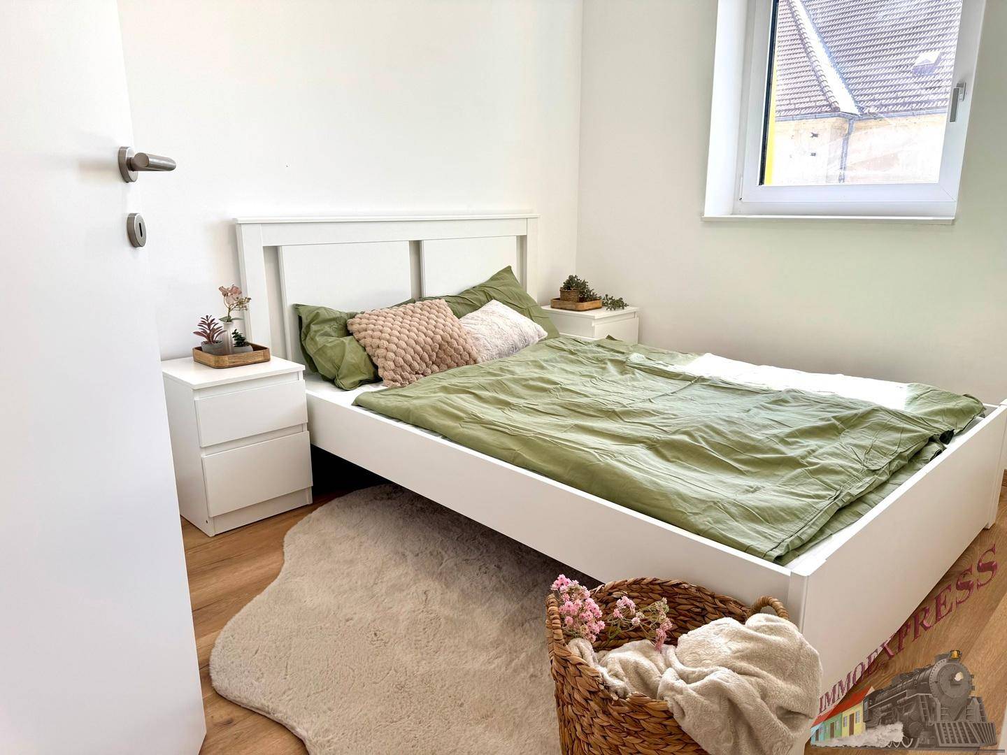 Gemütliches Schlafzimmer mit weißem Bett, Nachttischen und Holzboden, hell durch ein Fenster.