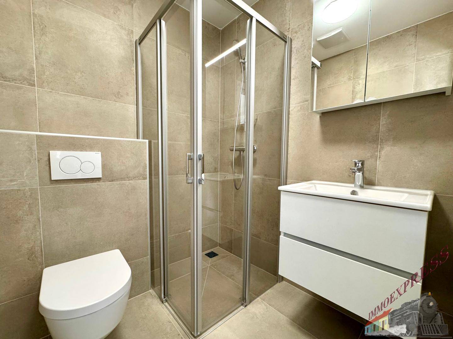Modernes Badezimmer mit Duschkabine, wandhängendem WC und Waschtisch, komplett gefliest.