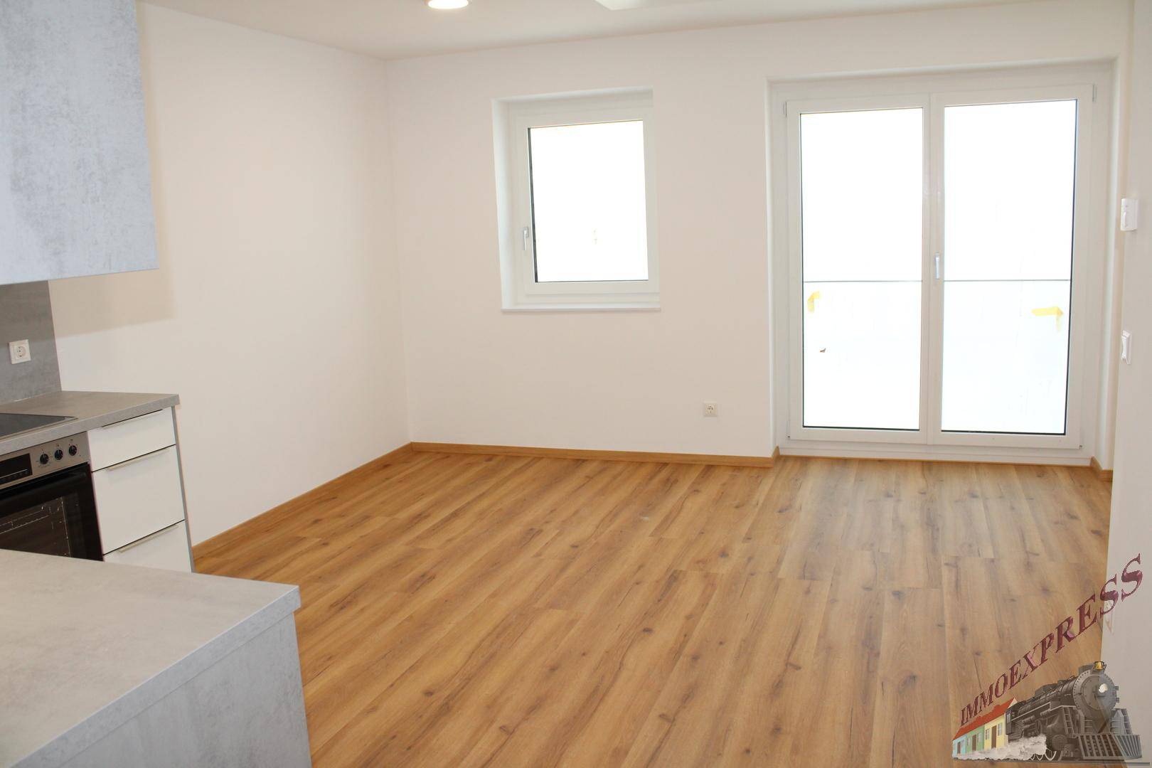 Geräumiger Wohnbereich mit Holzboden und großen Fenstern, bereit zur individuellen Gestaltung.