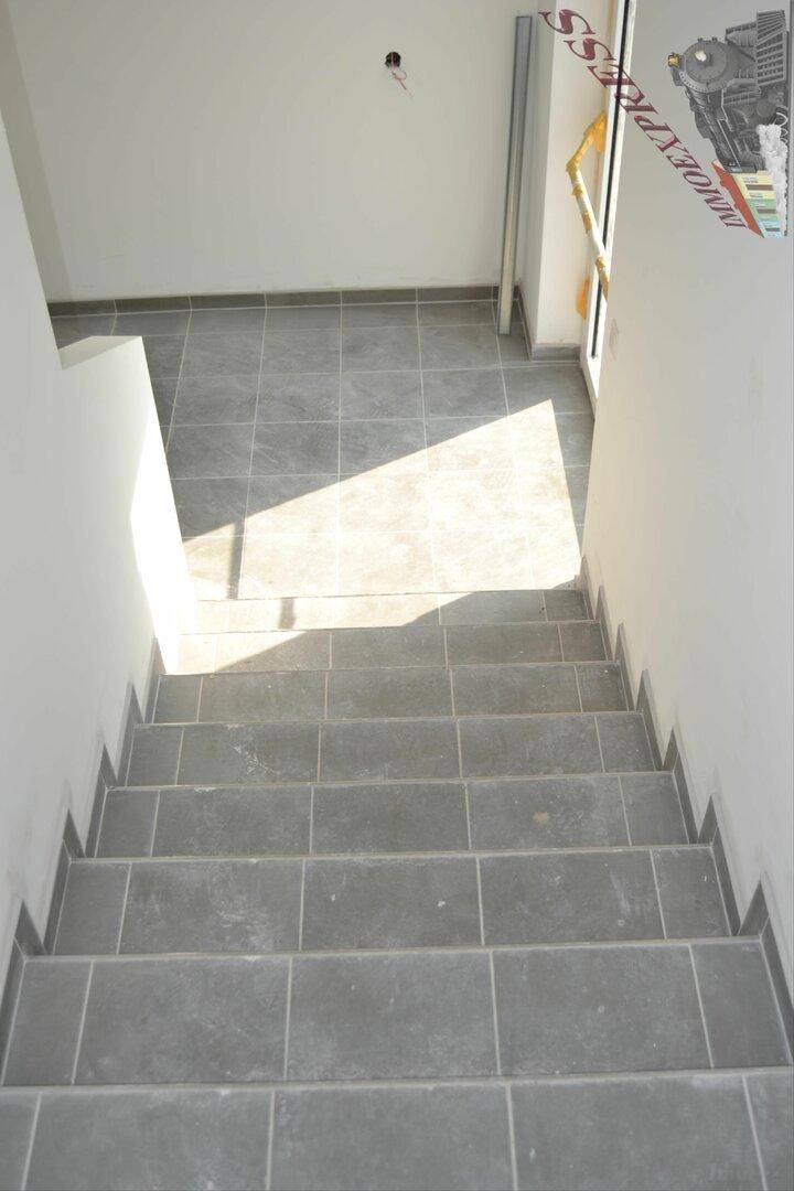 Geflieste Treppe mit grauen Fliesen, die nach unten führt, mit Sonneneinstrahlung.