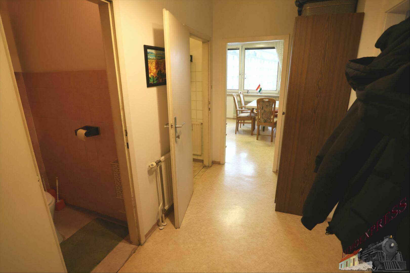 Langer Flur mit Zugang zu verschiedenen Räumen, inklusive einer Toilette.