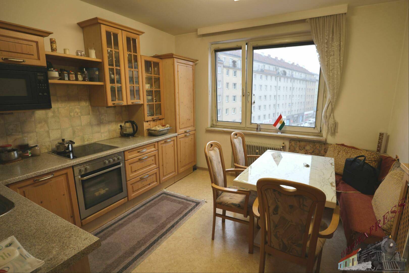 Gemütliche Wohnküche mit Essbereich am Fenster und Blick auf die Stadtbebauung.