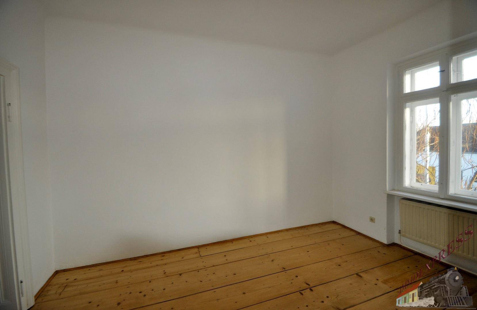 Leerer Raum mit Dielenboden, einem Fenster und weißen Wänden, bereit zur individuellen Gestaltung.
