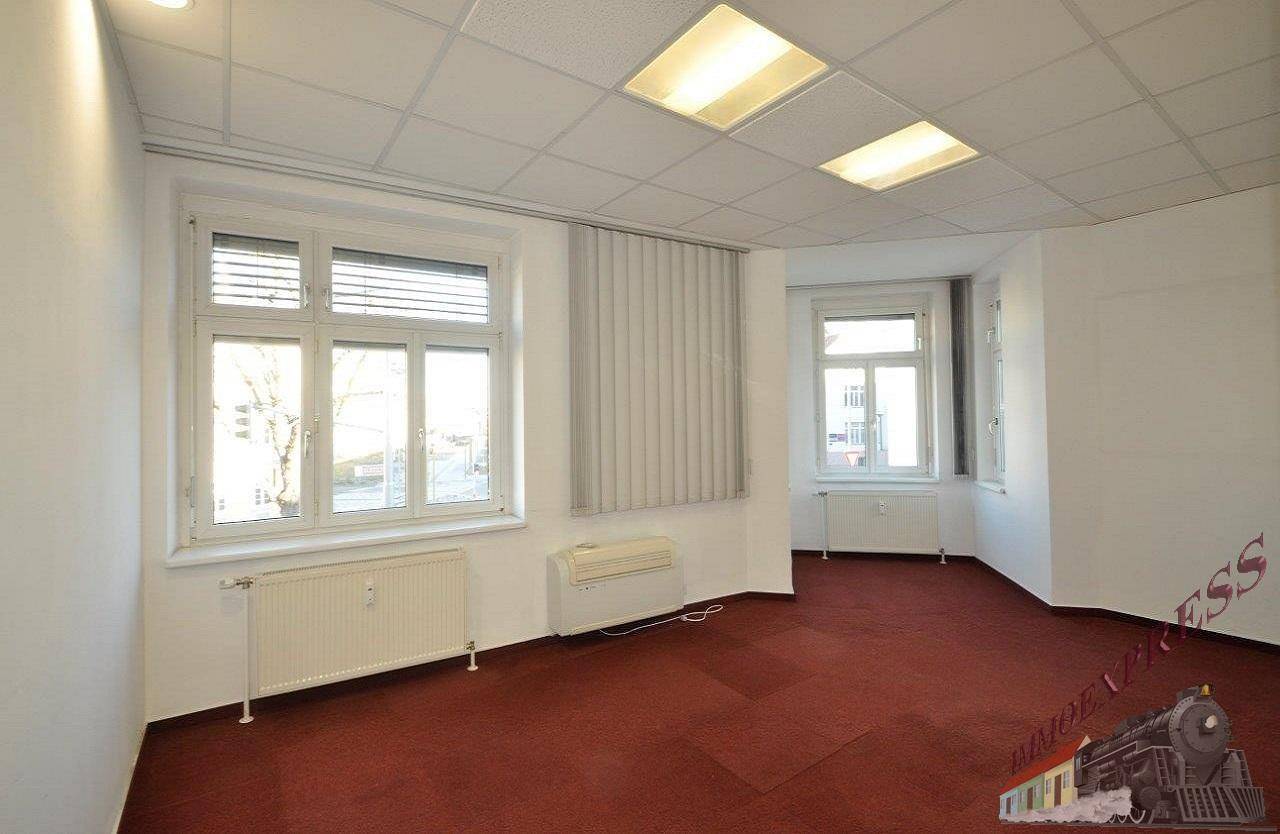 Helles Büro mit zwei Fenstern, die eine gute Belichtung bieten, und einem strapazierfähigen roten Teppichboden.