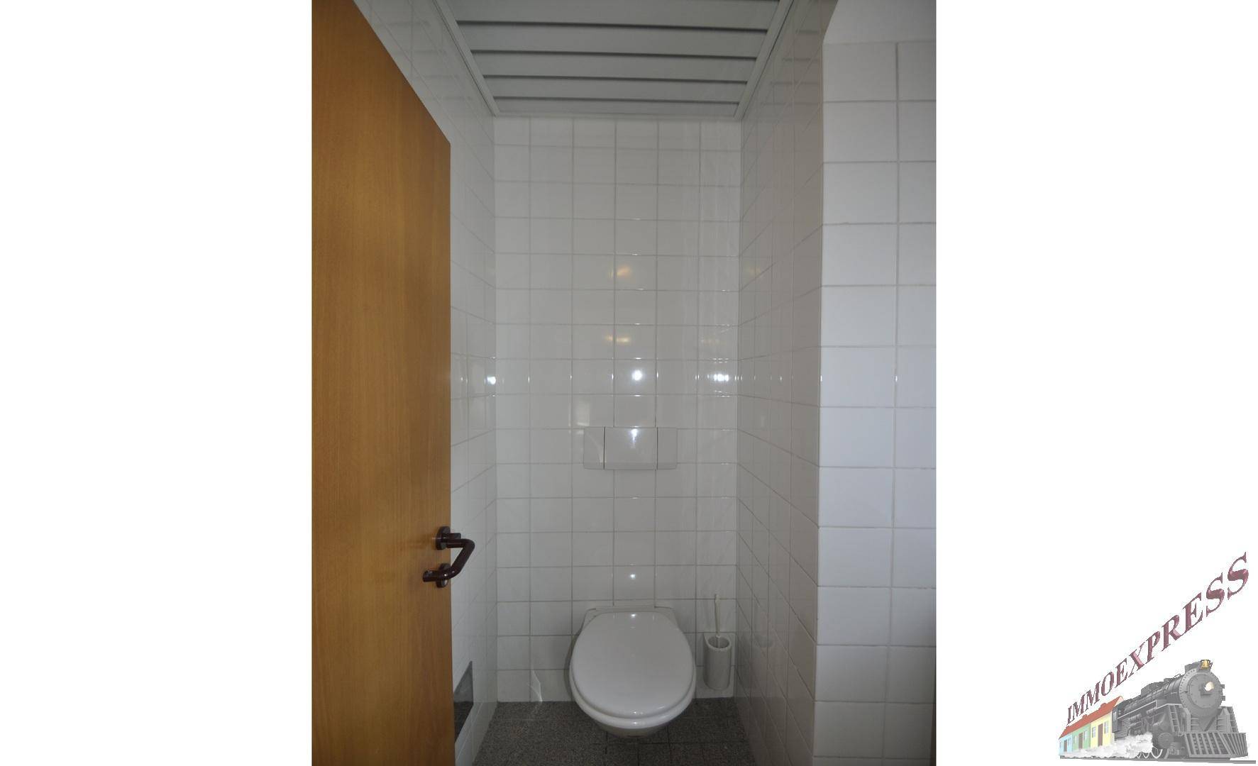 Saubere Toilette mit weißen Fliesen an Wänden und Boden, funktional und gepflegt.
