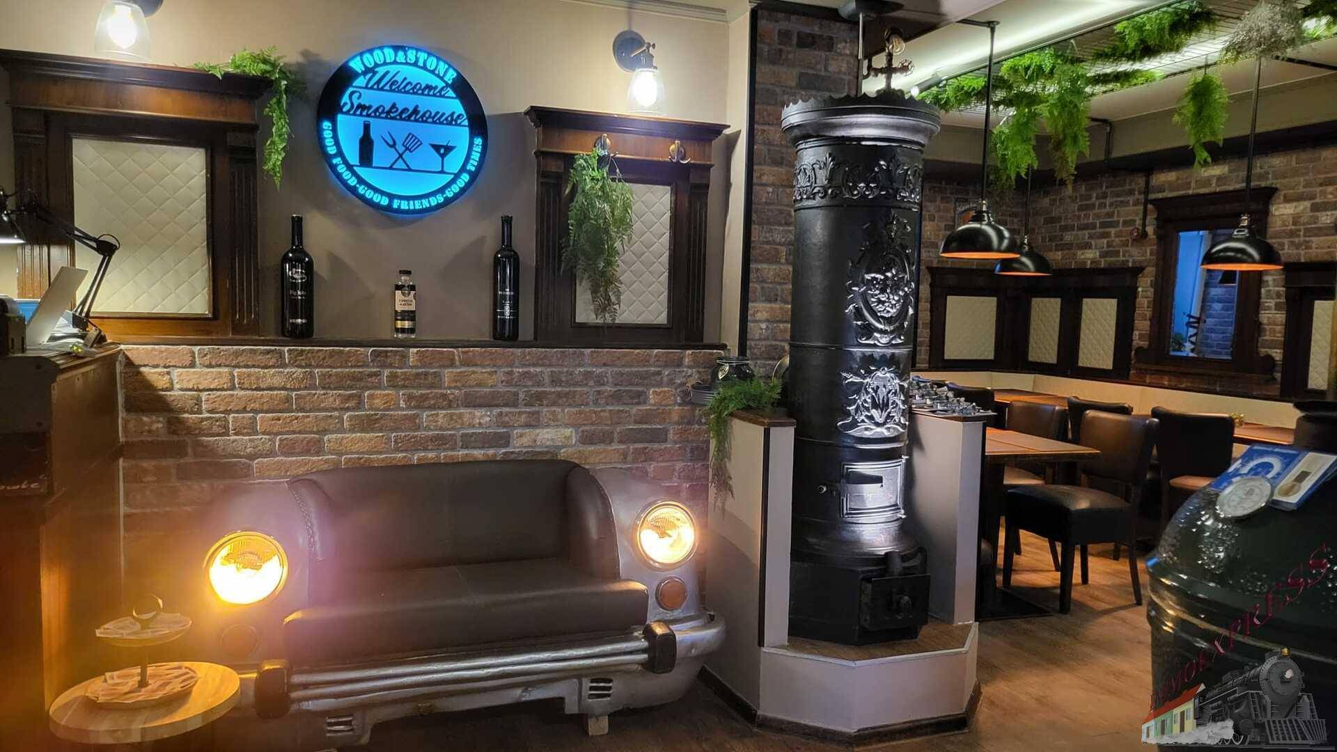 Einzigartiger Restaurantbereich mit einer Autosofa, einem dekorativen Ofen und einer Ziegelwand.