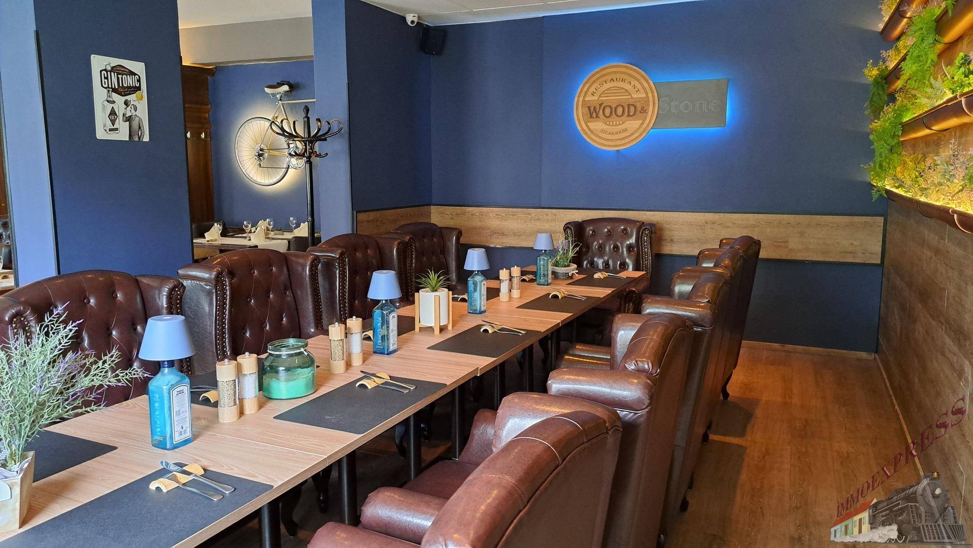 Langer Esstisch in einem Restaurant mit blauen Wänden, bequemen Ledersesseln und stilvoller Dekoration.