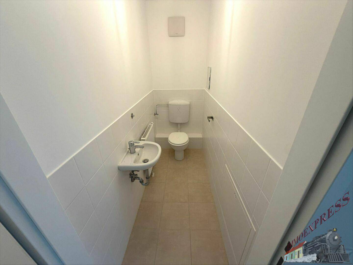 Kleines Gäste-WC mit Toilette, Waschbecken und weißen Fliesen, ausgestattet mit Abluftsystem.