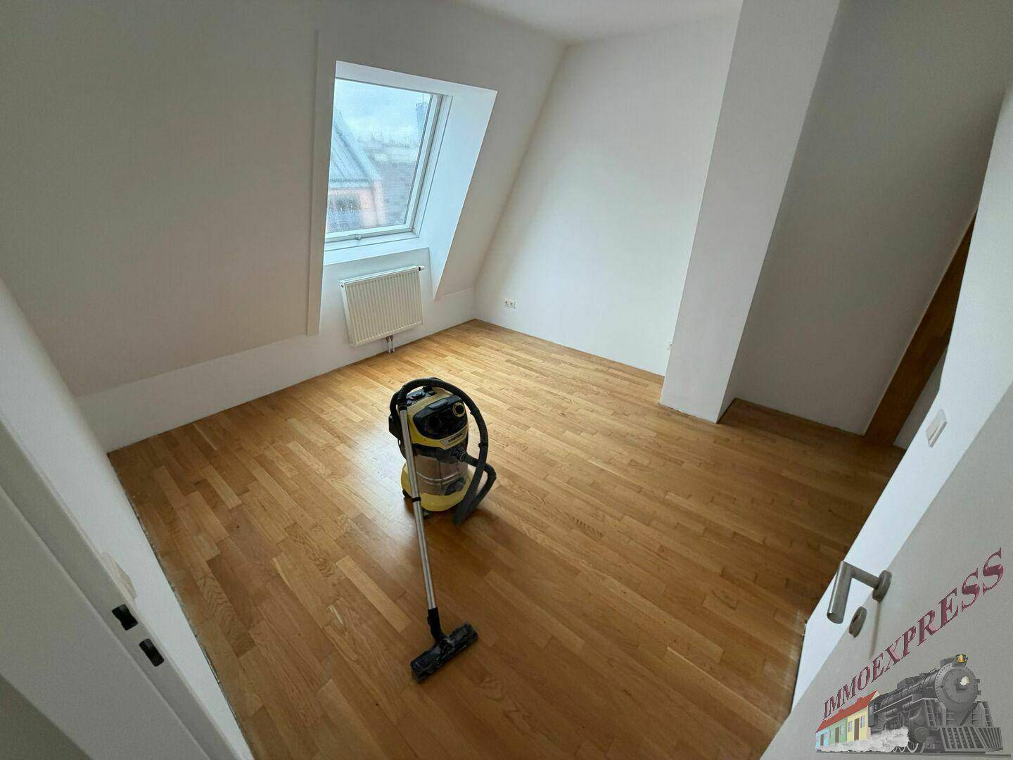 Sauberes Schlafzimmer im Dachgeschoss mit Holzboden und einem großen Dachfenster, bereit zum Einzug.