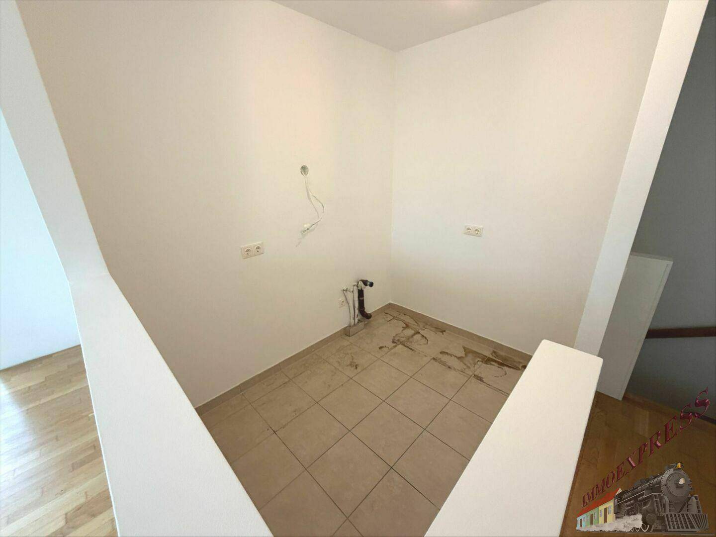 Detailansicht des gefliesten Bereichs mit Wasseranschlüssen, vorbereitet für eine Kücheninstallation.